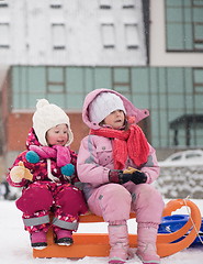 Image showing portrait of two little girls sitting together on sledges