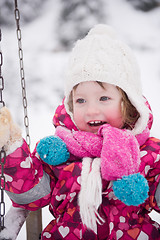 Image showing little girl at snowy winter day swing in park