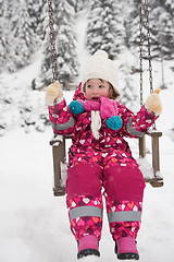 Image showing little girl at snowy winter day swing in park