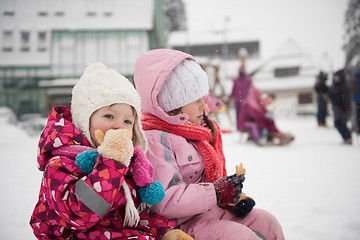 Image showing portrait of two little girls sitting together on sledges