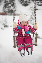 Image showing little girl at snowy winter day swing in park