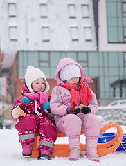 Image showing portrait of two little girls sitting together on sledges