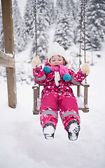 Image showing little girl at snowy winter day swing in park