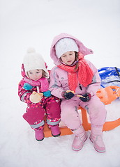 Image showing portrait of two little girls sitting together on sledges