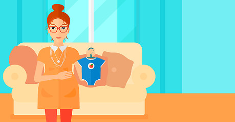 Image showing Pregnant woman with clothes for baby.