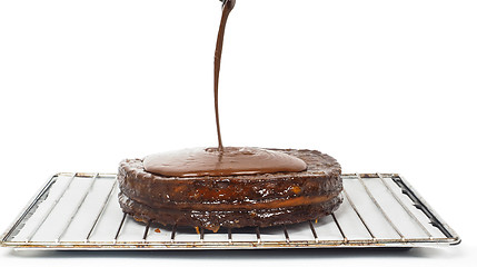 Image showing Closeup of chocolate icing pouring over Sacher torte towards whi