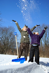 Image showing mother and her daughter throw up snow on a winter background