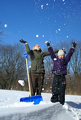 Image showing mother and her daughter throw up snow on a winter background