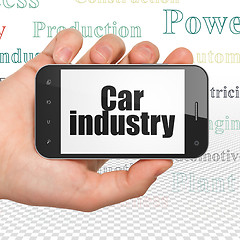 Image showing Manufacuring concept: Hand Holding Smartphone with Car Industry on display