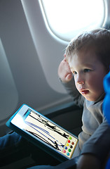 Image showing Little boy drawing on a tablet in an airplane