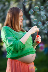 Image showing Pregnant woman blowing bubbles outdoor