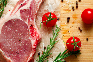 Image showing Pieces of crude meat with rosemary and tomatoes.