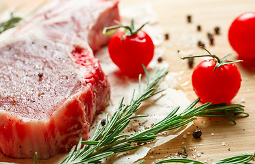 Image showing Pieces of crude meat with rosemary and tomatoes.