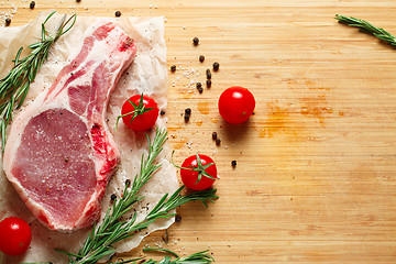 Image showing Pieces of crude meat with rosemary and tomatoes.