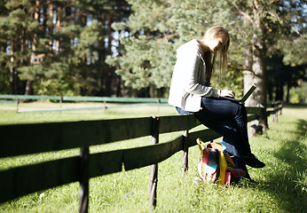 Image showing Young woman sitting on a rustic fence