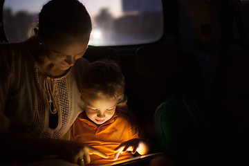 Image showing Mother and son with pad during car travel at night