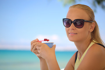 Image showing Young woman eating ice-cream on the beach