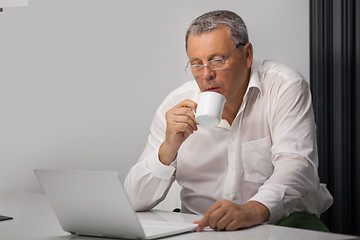 Image showing Businessman drinking coffee while working in office