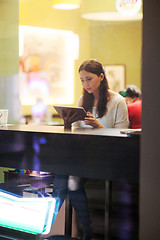 Image showing Young brunette girl using tablet in the cafe