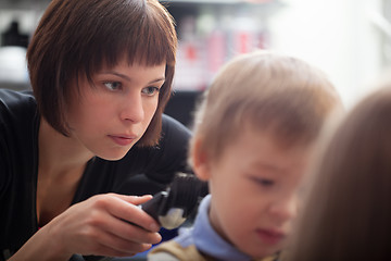 Image showing Hairstylist cutting a young boys hair