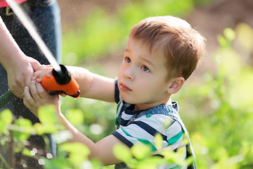 Image showing Little boy playing with a jet of water in garden