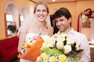 Image showing Smiling bride and groom with bouquets of flowers