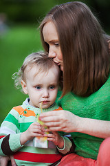 Image showing Mother kissing the child drinking juice outdoor