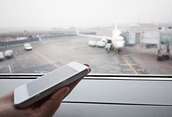 Image showing Hand with smart phone by the window at airport