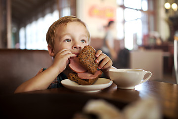 Image showing Little child having lunch with sandwich and tea in cafe