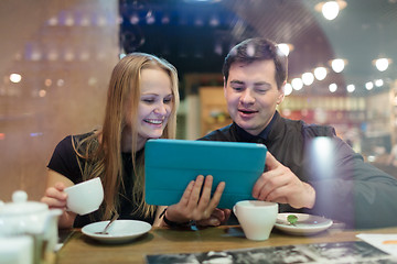 Image showing Young people drinking coffee and looking on pad