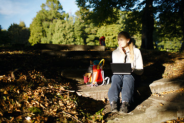 Image showing Young woman working outdoors on a laptop