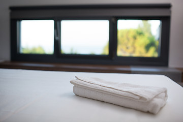 Image showing Clean white towel on the bed in hotel room