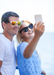 Image showing Cheerful couple in sunglasses taking mobile selfie