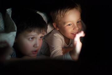 Image showing Two boys watching movie or cartoon on pad at night