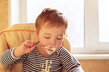 Image showing Two year old boy eats porridge in the morning.