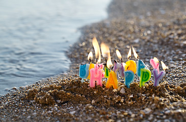 Image showing Birthday candles burning on a seashore