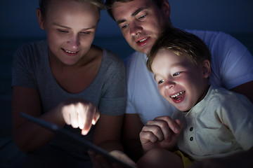 Image showing Parents and son with tablet PC outdoor late in the evening