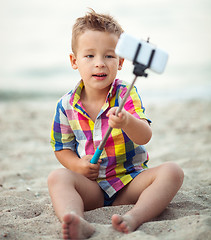Image showing Child with phone and selfie stick on the beach