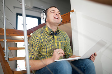 Image showing Excited hipster man relaxing with music and laptop