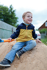 Image showing Happy little boy sitting on sand hill