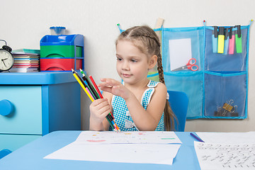 Image showing Happy five year old girl picked up a colored pencils and choose the right pencil