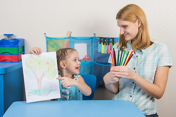 Image showing Five-year girl showing on the picture and looked at my mother who is holding in the hands of colored pencils