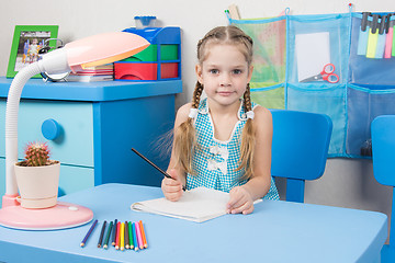 Image showing Five-year girl draws pencil in a notebook and looked into the frame