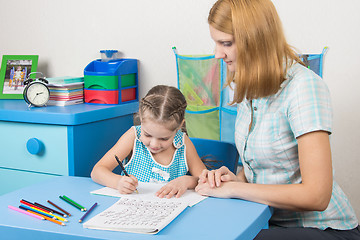 Image showing Five-year girl learns to write letters correctly, a tutor helps her