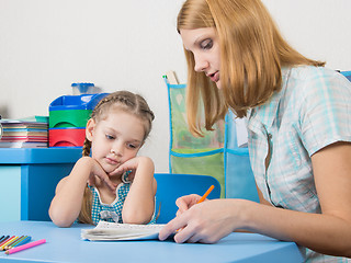 Image showing Five-year girl with interest looking notebook and listening to the explanation of the teacher