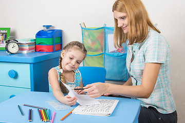 Image showing Tutor checks the job done on a piece of a five-year girl