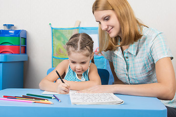 Image showing Tutor sees that the child turns out to write letters of the alphabet