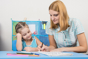 Image showing A young girl explains the five-year girl how to write letters