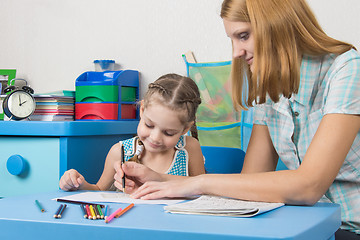 Image showing A teacher helps a five-year girl with a ruler to draw