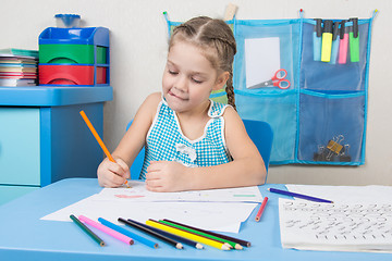 Image showing Five-year girl stuck out her tongue with pleasure, drawing picture at table